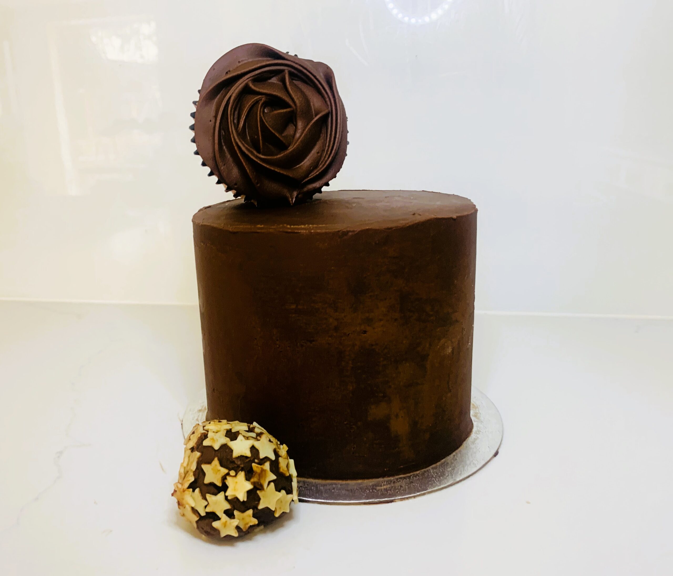 Cake covered in dark chocolate ganache, cupcake with dark chocolate swirl piped icing and dark chocolate truffel with white chocolate stars